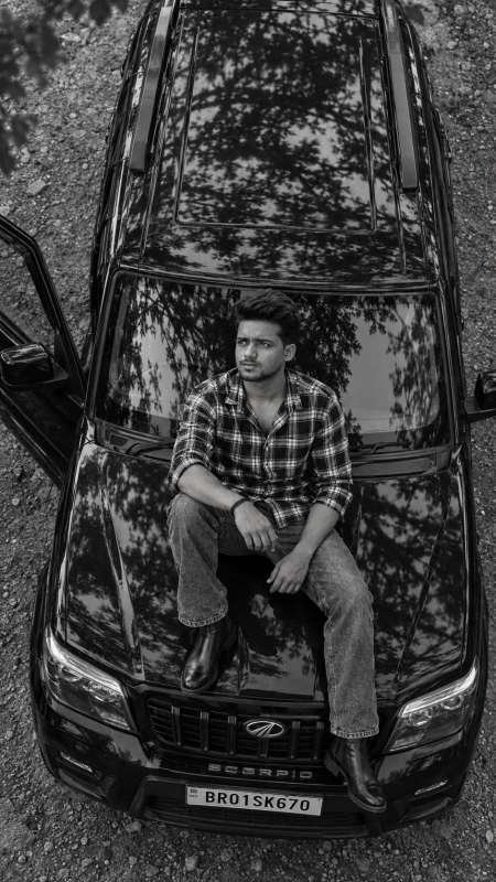 Scorpio photo editing prompt - A young stylish Indian man sitting on the